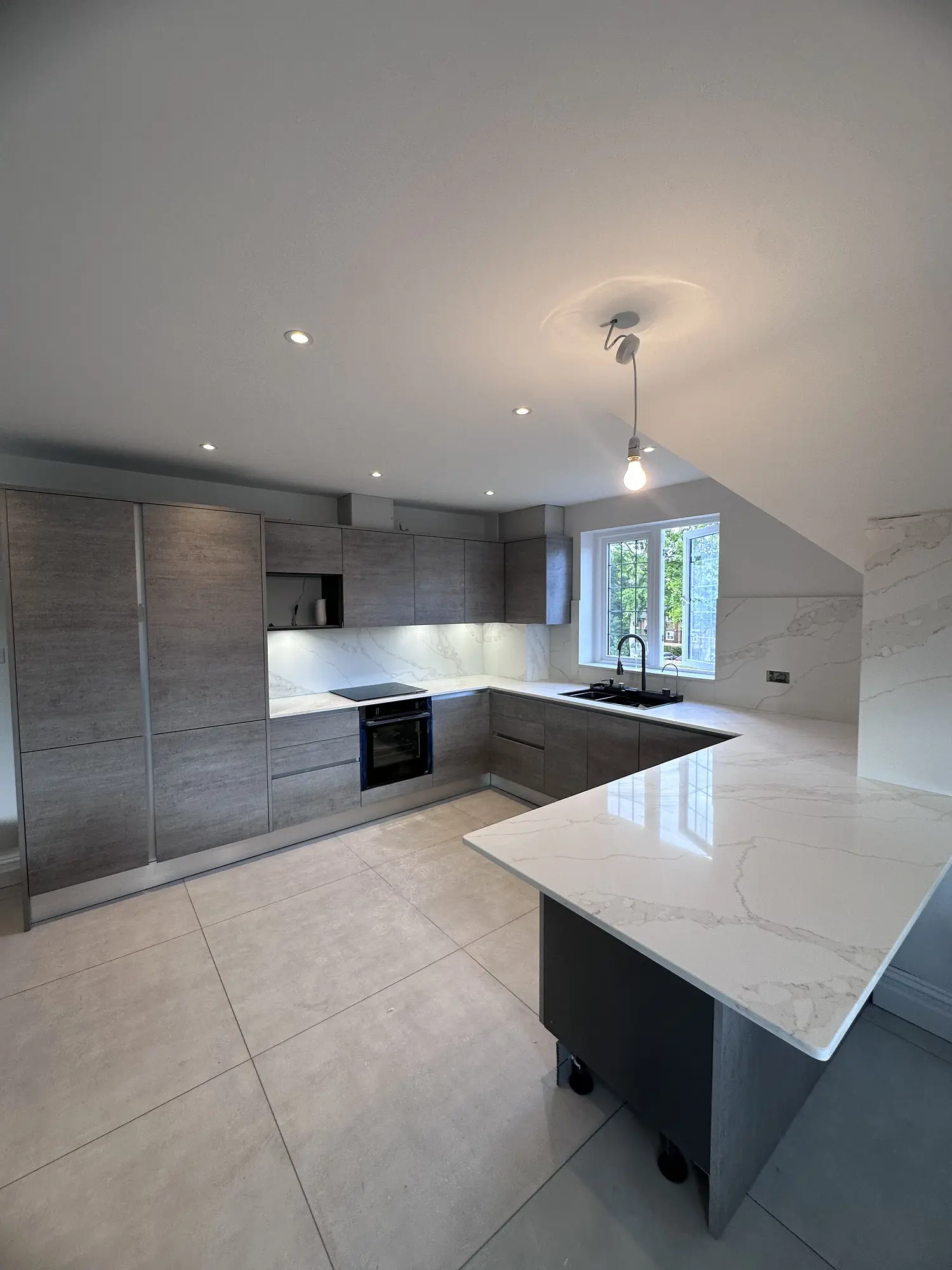 Contemporary grey kitchen with marble-effect worktops and a large peninsula