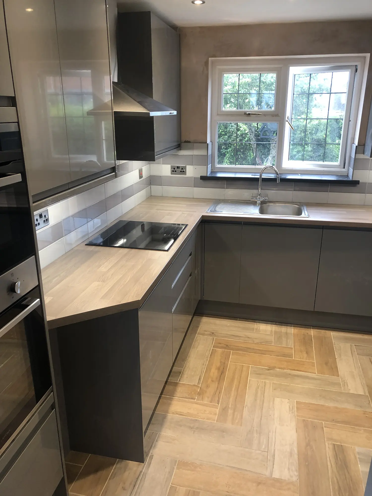 Warm grey herringbone kitchen with timber-effect worktops